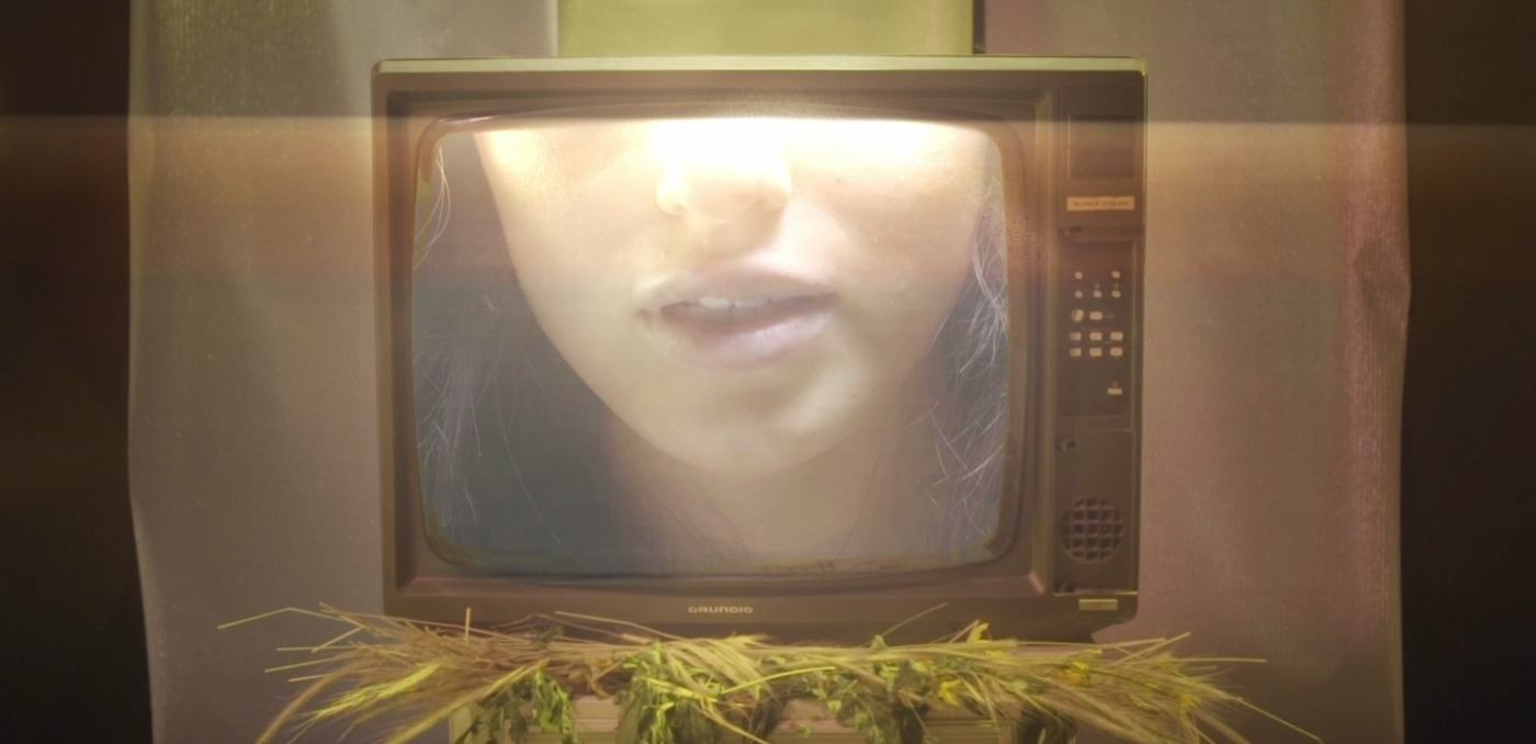 A woman's face lit in pink and teal against a mosaic of mirrored tiles (1/9)