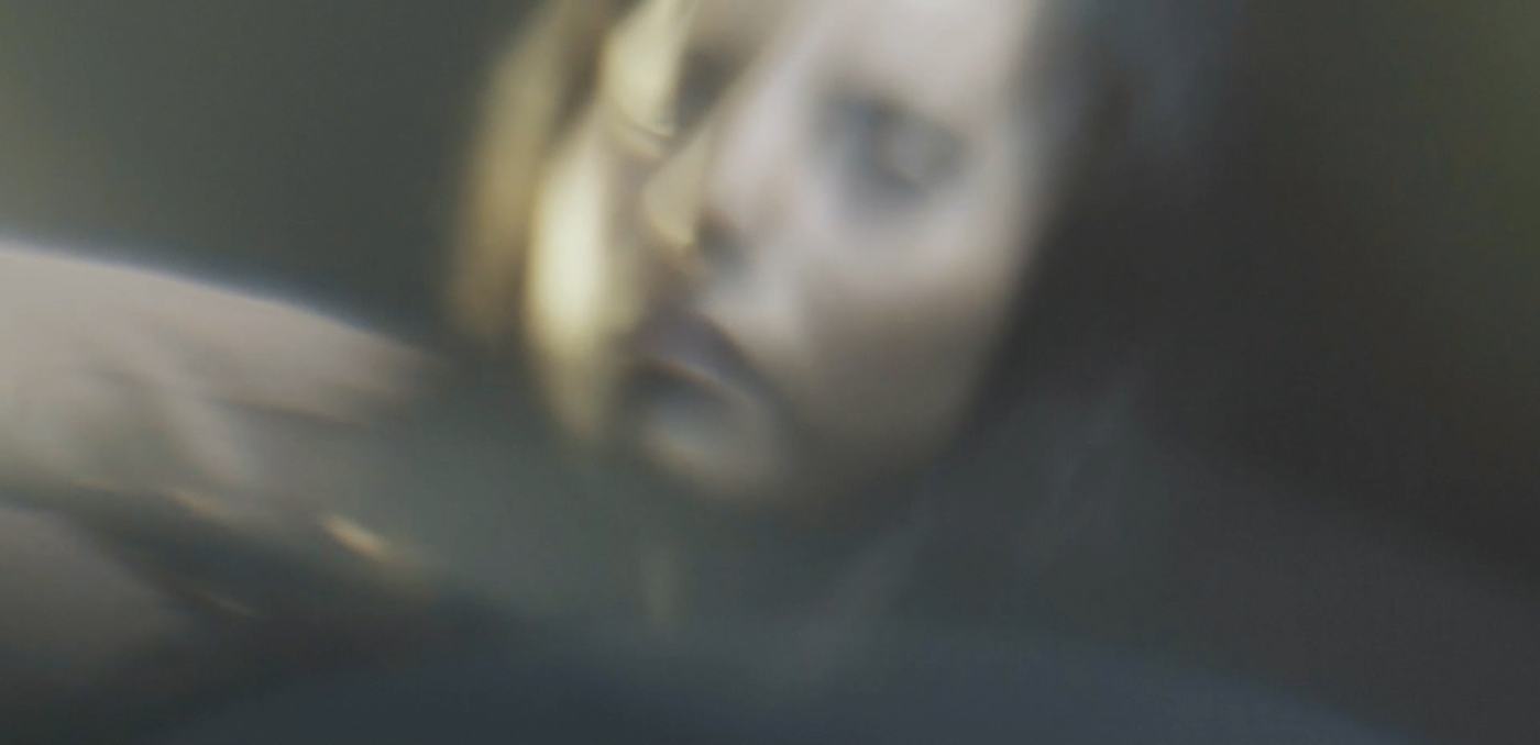 A woman's face lit in pink and teal against a mosaic of mirrored tiles (2/9)