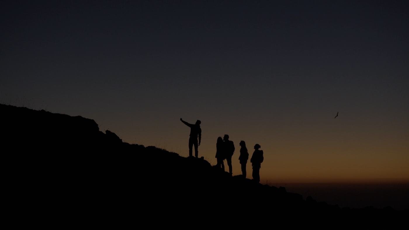 People gathered around a campfire at night on a mountainside (2/12)