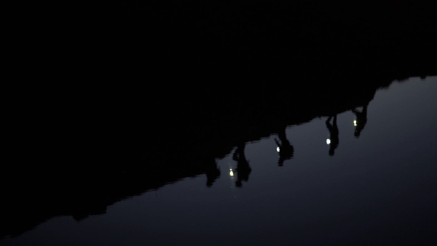People gathered around a campfire at night on a mountainside (3/12)