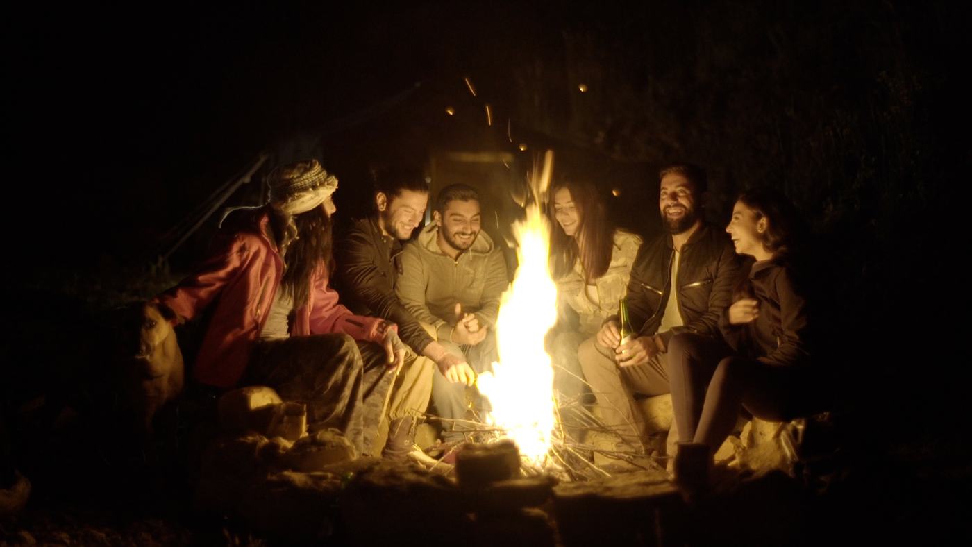People gathered around a campfire at night on a mountainside (5/12)