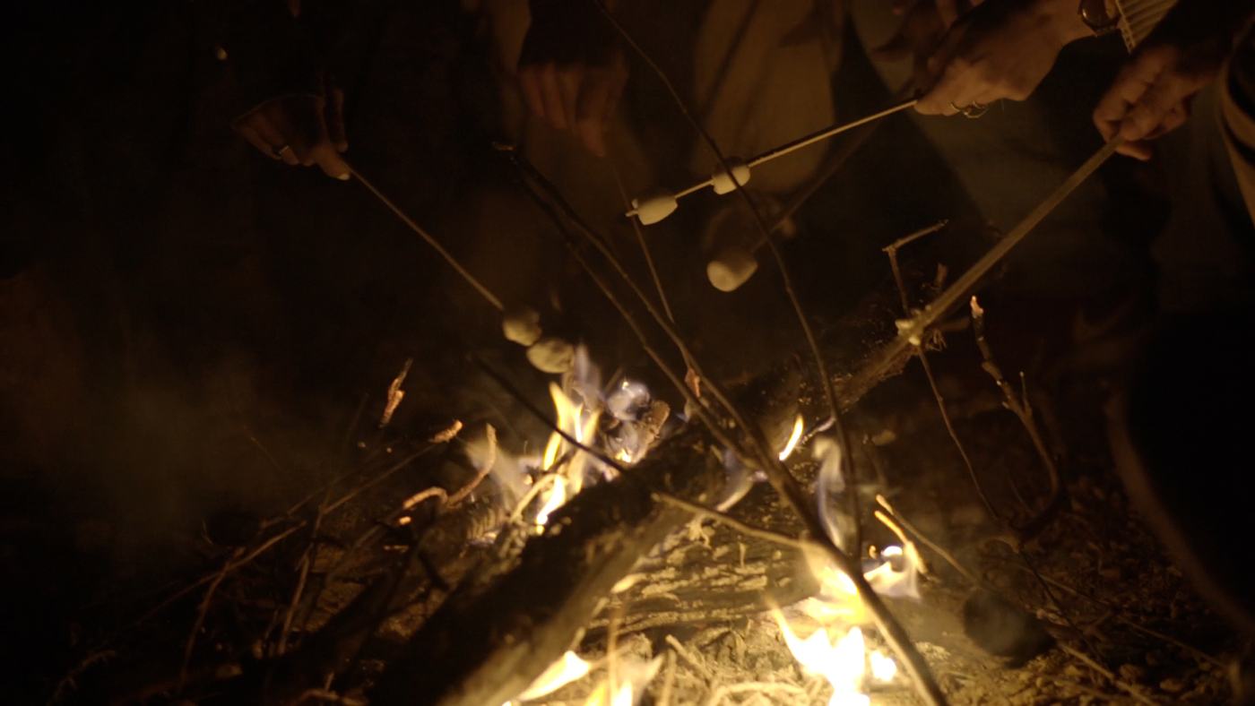 People gathered around a campfire at night on a mountainside (6/12)