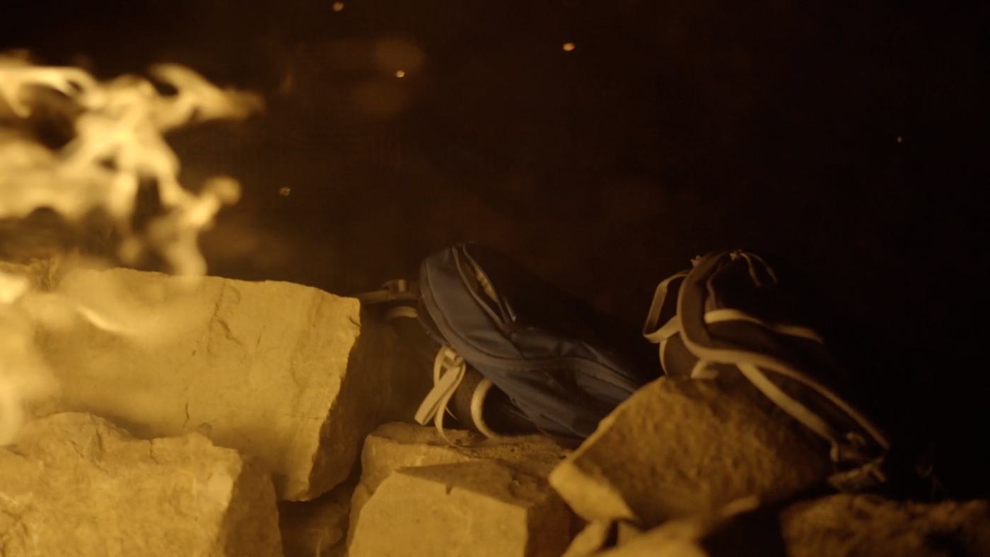 People gathered around a campfire at night on a mountainside (7/12)