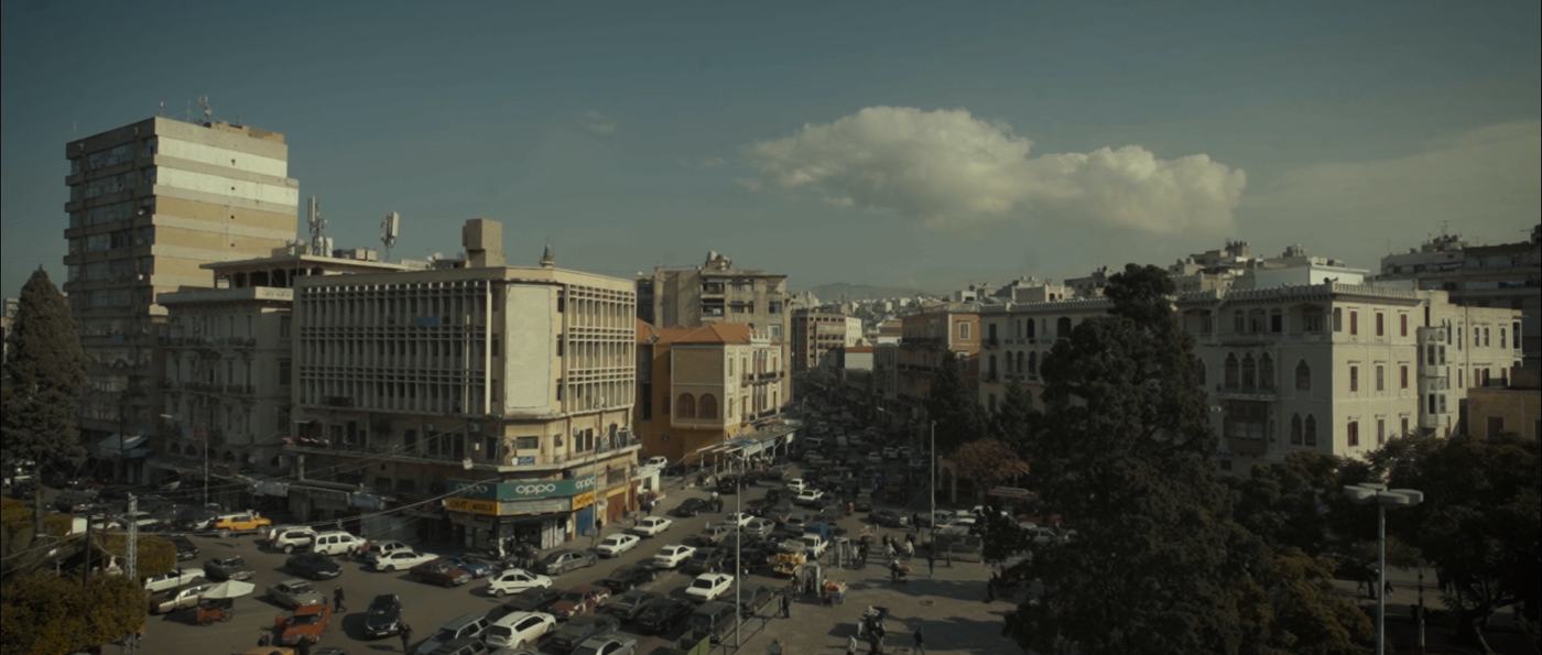 A bearded man in a plaid shirt on a rooftop above a city (1/14)