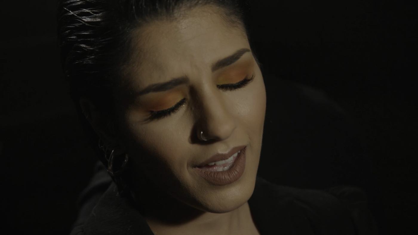 A woman sings with her eyes closed in low light (2/9)