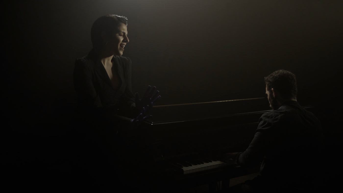 A woman sings with her eyes closed in low light (6/9)