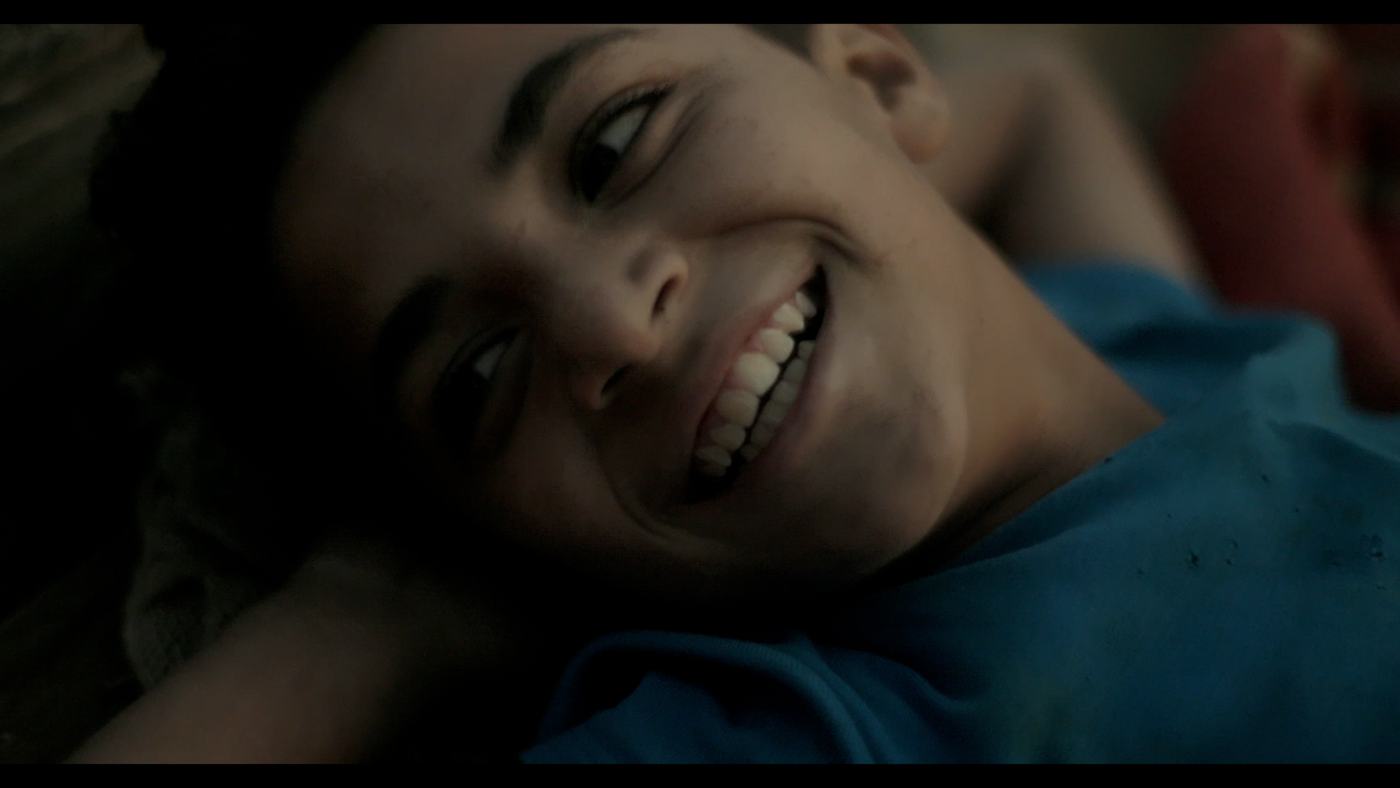 A boy in a blue shirt looks off-frame in a dim truck cab (1/12)