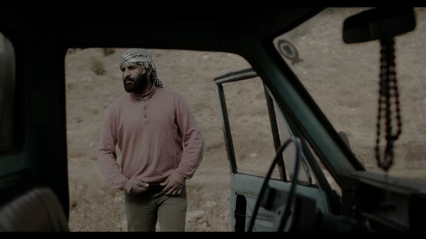 A boy in a blue shirt looks off-frame in a dim truck cab (5/12)