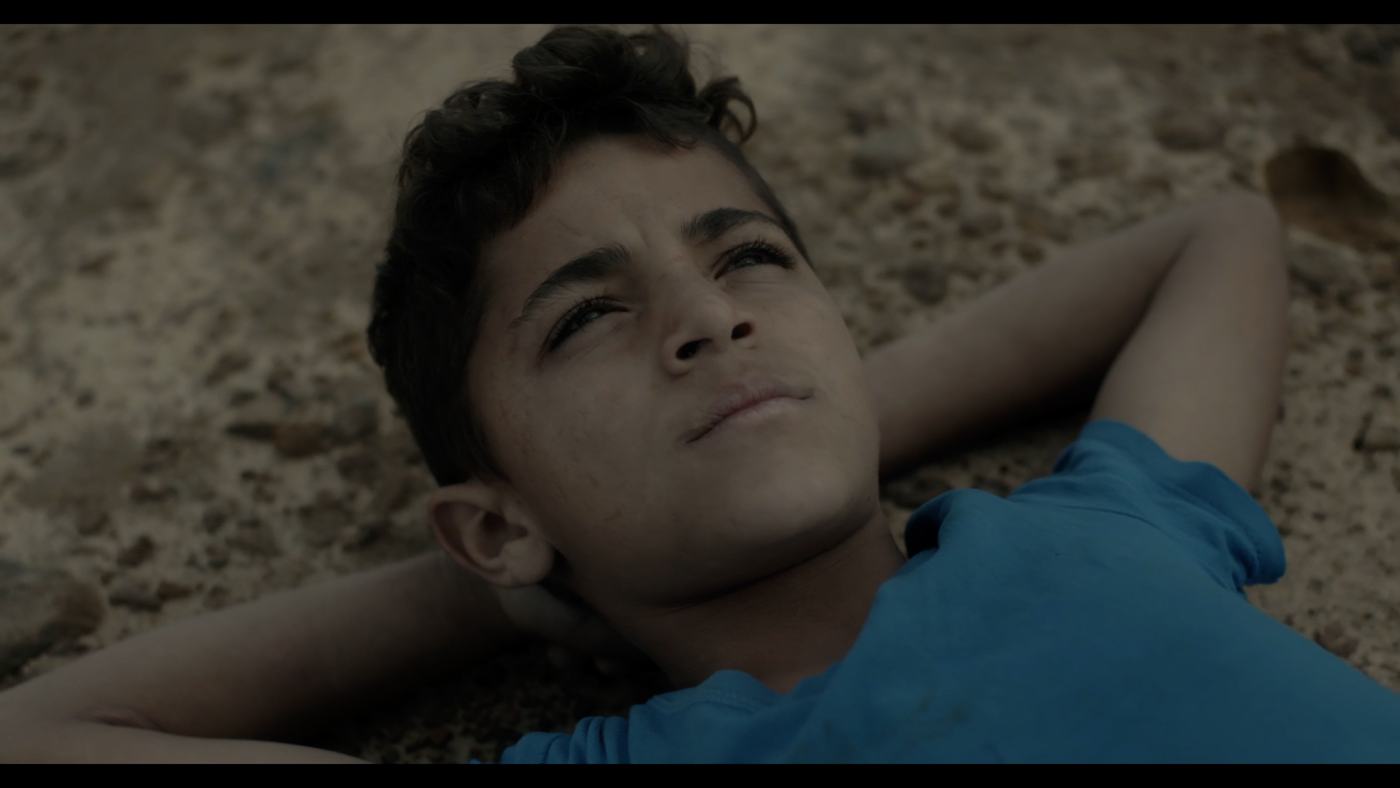 A boy in a blue shirt looks off-frame in a dim truck cab (8/12)