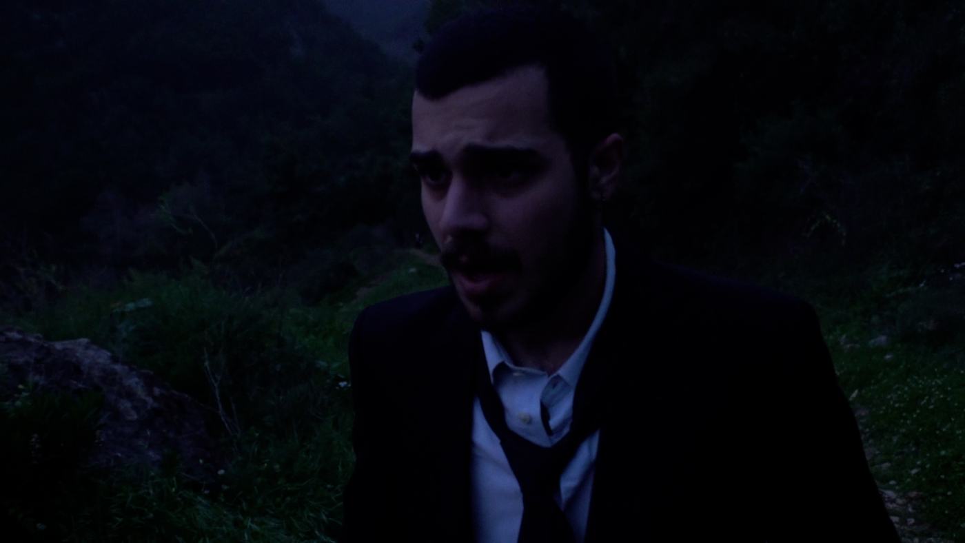 A man in blue and green light lies back, eyes open (13/15)