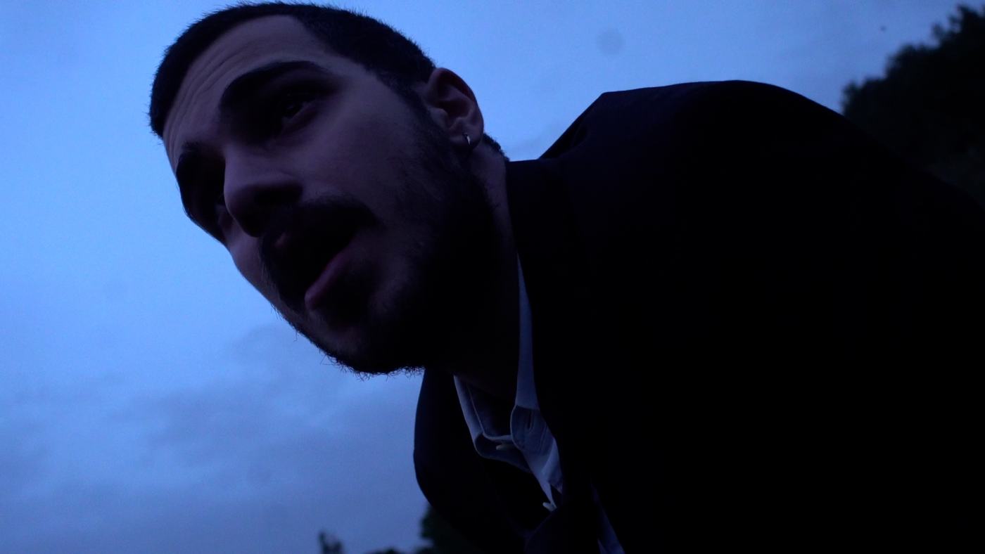 A man in blue and green light lies back, eyes open (14/15)